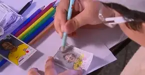 Menino faz à mão um criativo álbum de figurinhas da Copa
