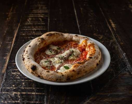 Bia Limoni misturou tomates San Marzano, alici e parmesão com a leveza da stracciatella e a fragrância da manjerona.