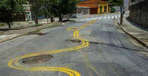 Moradores de rua esburacada pintam ao redor dos buracos em SP