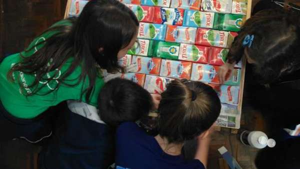 Estudantes montando a biblioteca com caixas de leite