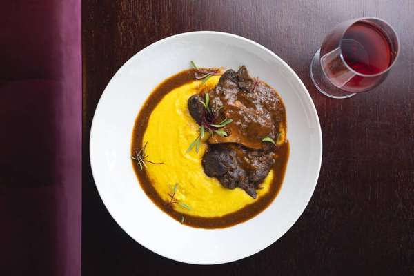 Polenta Cremosa com Ossobuco alla Milanese (R$119), preparada lentamente com manteiga e parmesão, servida com ossobuco bovino cozido por horas em vinho