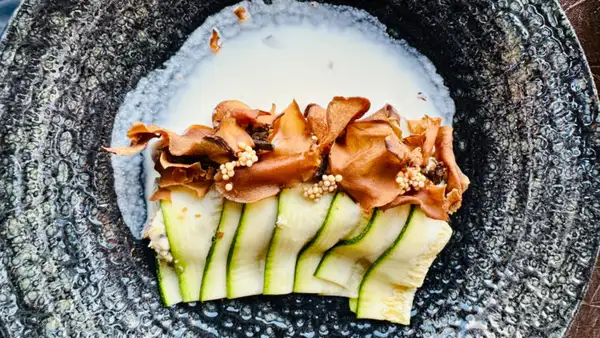 Vegano: canelone de abobrinha, recheado com creme de grão de bico, com lâminas de cogumelos e calda de amêndoas